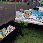 Thumbnail: White table with display of picture books of different colors next to a black cart with more picture books on display