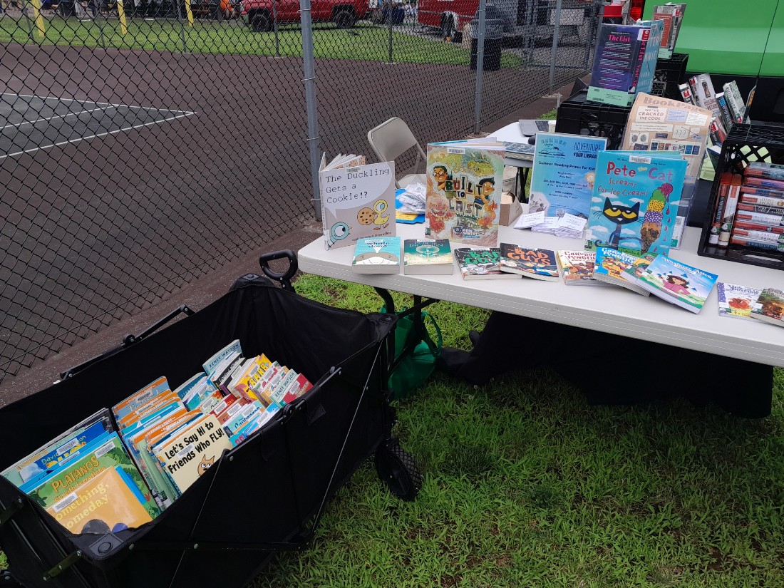 White table with display of picture books of different colors next to a black cart with more picture books on display